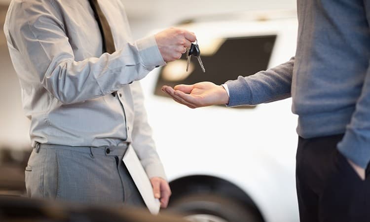 Eine Person übergibt einen Autoschlüssel an eine andere Person.